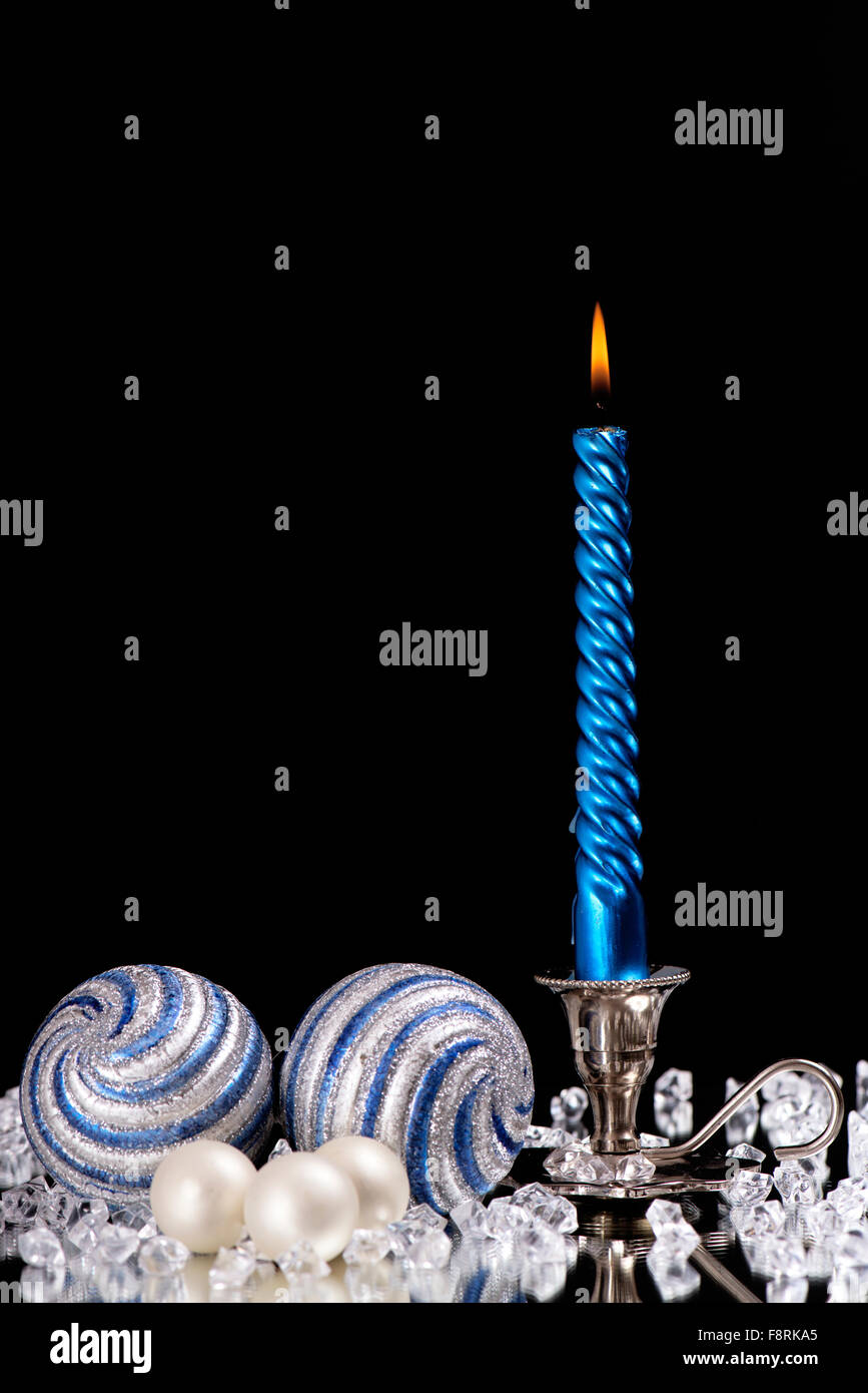 Argento candelabro con una candela blu e palle di vetro sorge accanto ad una moltitudine di pietre di cristallo sul mirror Foto Stock