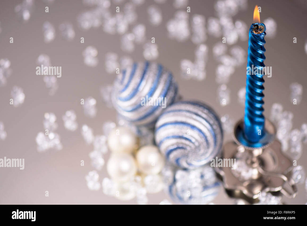 Argento candelabro con una candela blu e palle di vetro sorge accanto ad una moltitudine di pietre di cristallo sul mirror Foto Stock