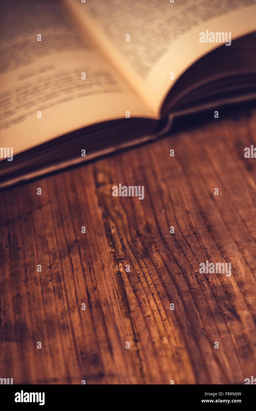 Vecchio libro libreria in legno scrivania con testo illeggibile, dai toni rétro immagine, il fuoco selettivo Foto Stock