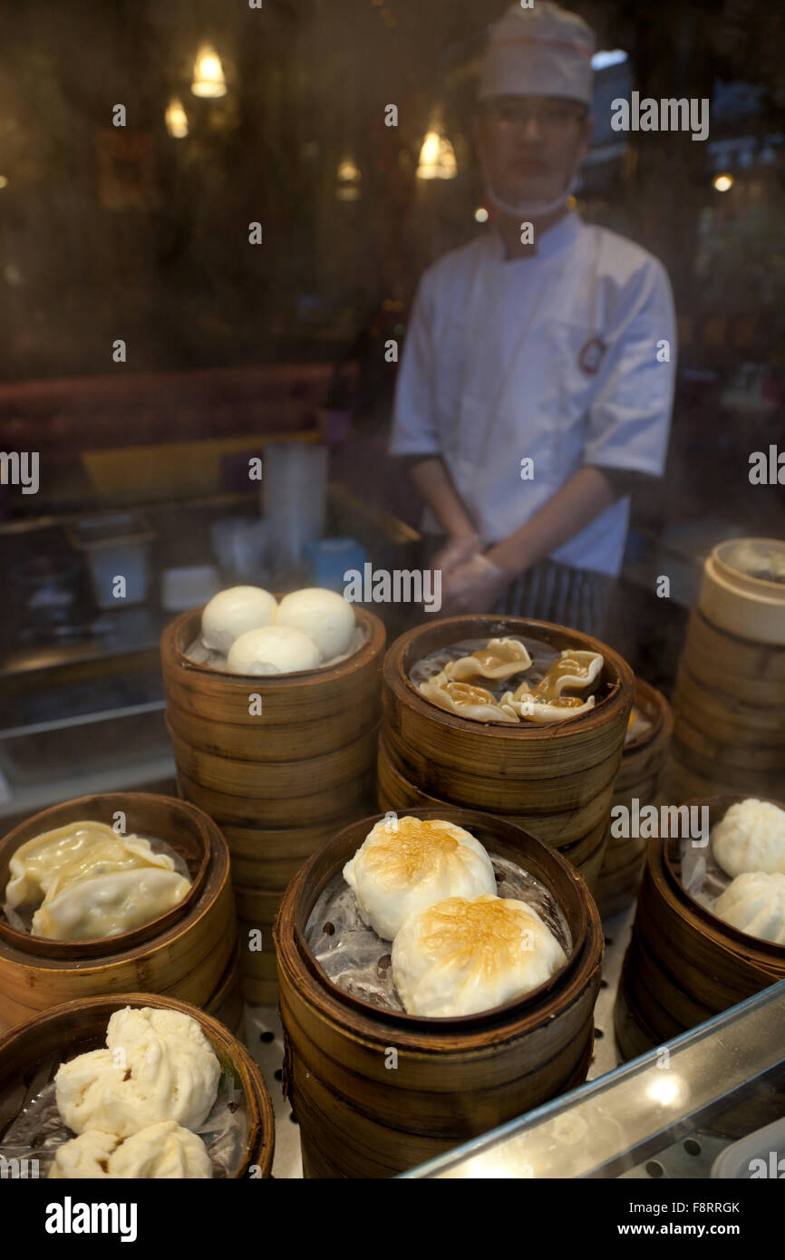 Un cuoco della cottura a vapore dim sum in bambù piroscafi presso un ristorante in Cina. Foto Stock