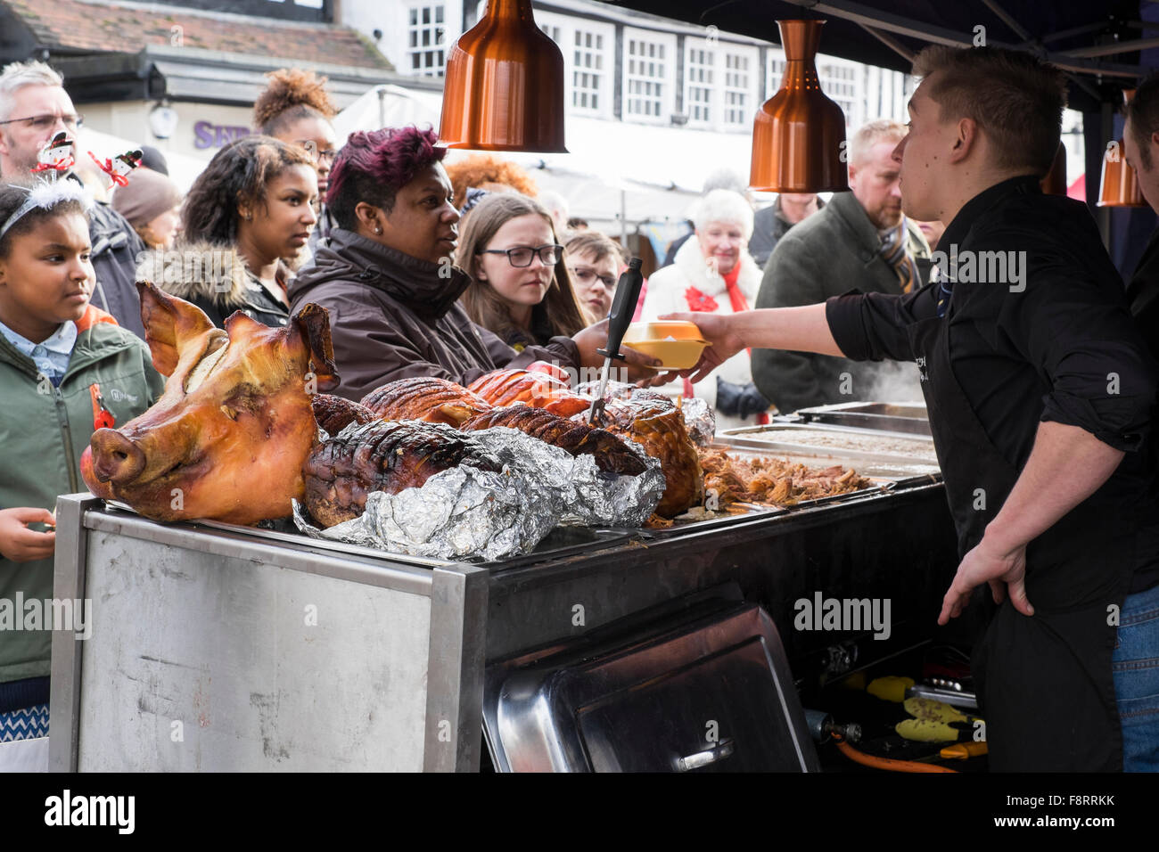 Una testa di suini su una fase di stallo in quanto i clienti in coda per carne di maiale caldi rotoli di Bridgnorth mercatino di Natale, Shropshire, Inghilterra, Regno Unito Foto Stock