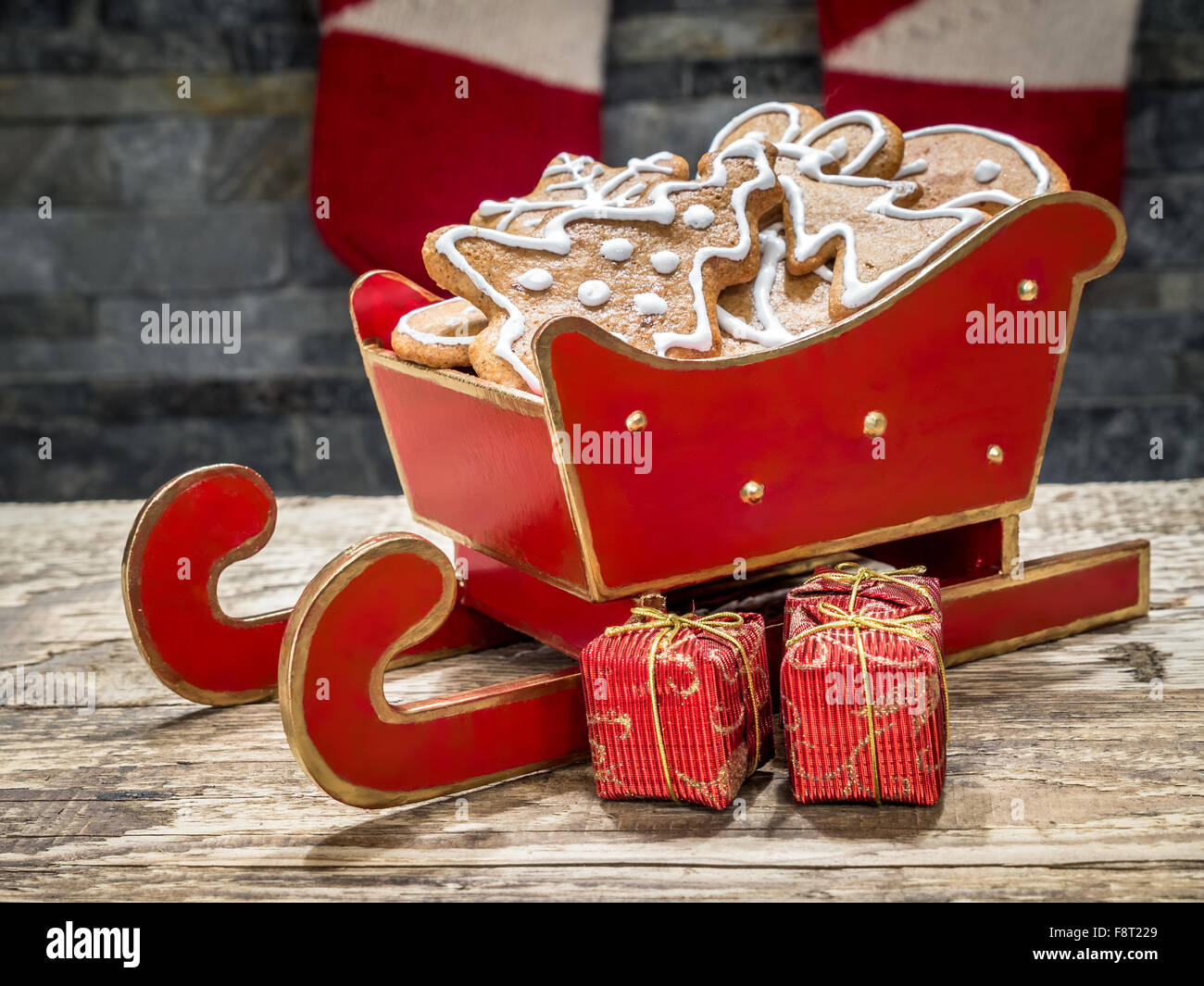 Assortiti di panpepato di Natale i biscotti con la glassa bianca in red mini sleigh collocato sul tavolo Foto Stock