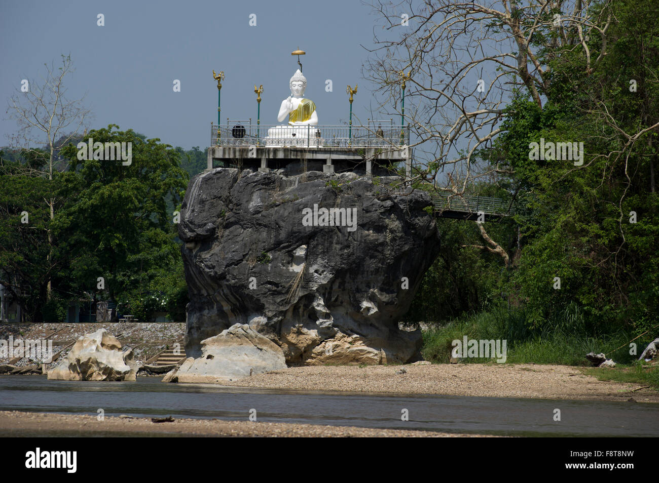 White statua del Buddha su un gigante di roccia lungo il fiume in Thailandia del Nord nei pressi di Chaing Rai Foto Stock