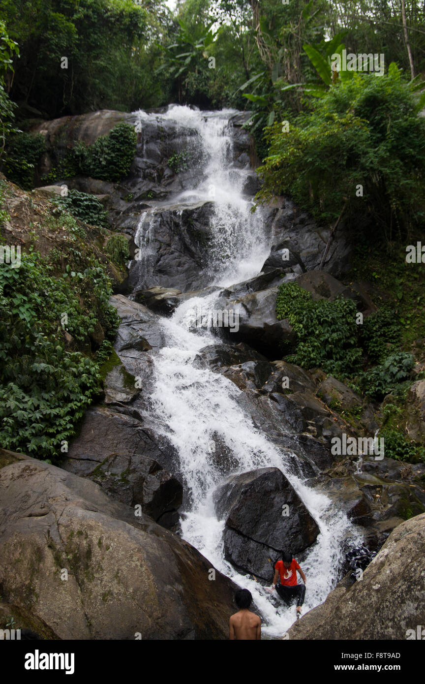 Ragazzi tailandese seduto su una roccia e giocando in una cascata in un parco nazionale vicino a Chiang Rai, Thailandia, Sud-est asiatico Foto Stock