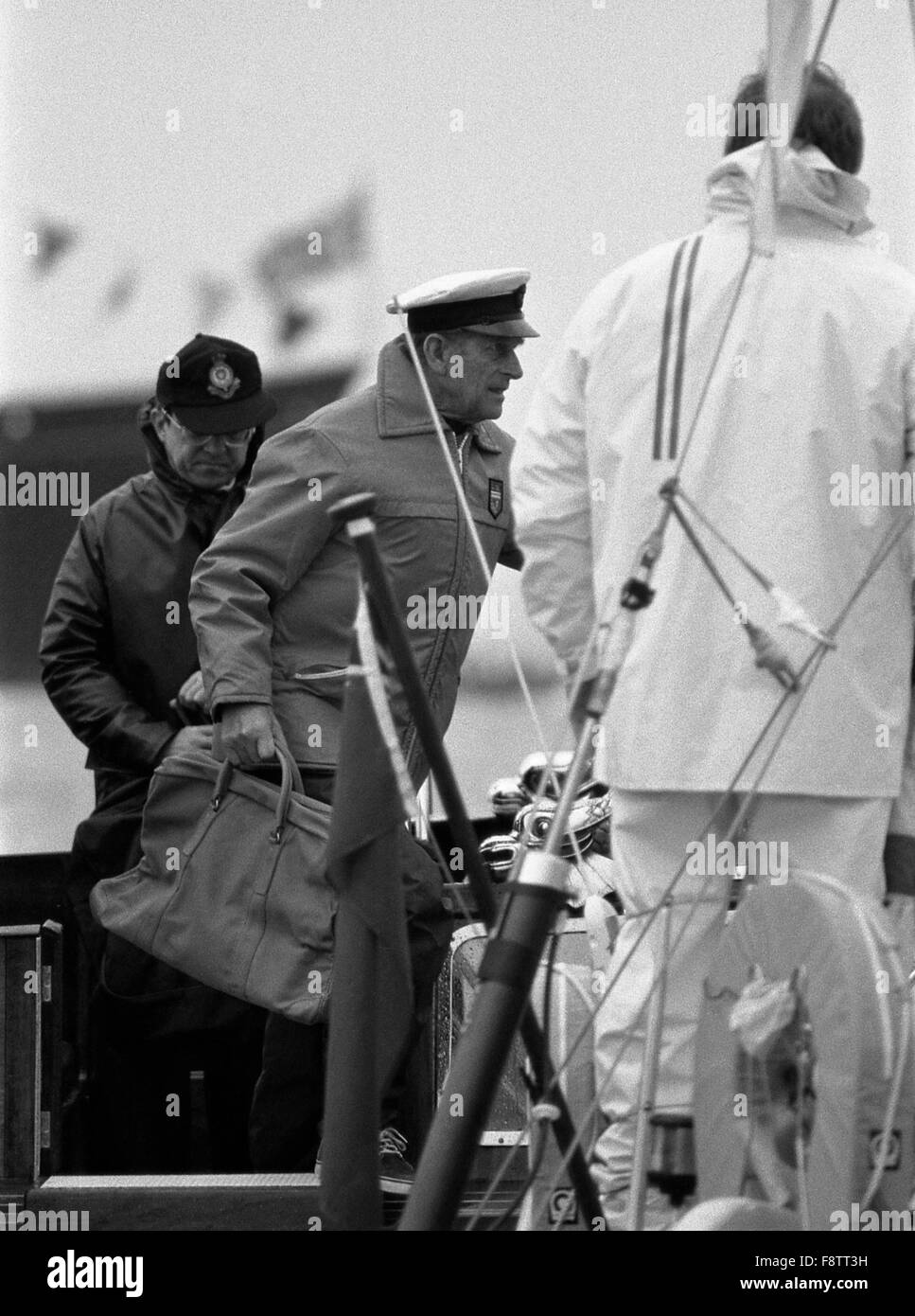 AJAXNETPHOTO. Agosto, 1985. COWES, Inghilterra, - DUKE SI UNISCE YACHT - S.A.R. il Principe Filippo del Duca di Edimburgo lasciando il Royal Barge A BORDO OWEN AISHER'S YEOMAN VENTI PER IL BRITANNIA Cup gara. Il Royal Yacht Britannia in background. Foto;JONATHAN EASTLAND/AJAX REF:860308 20 Foto Stock