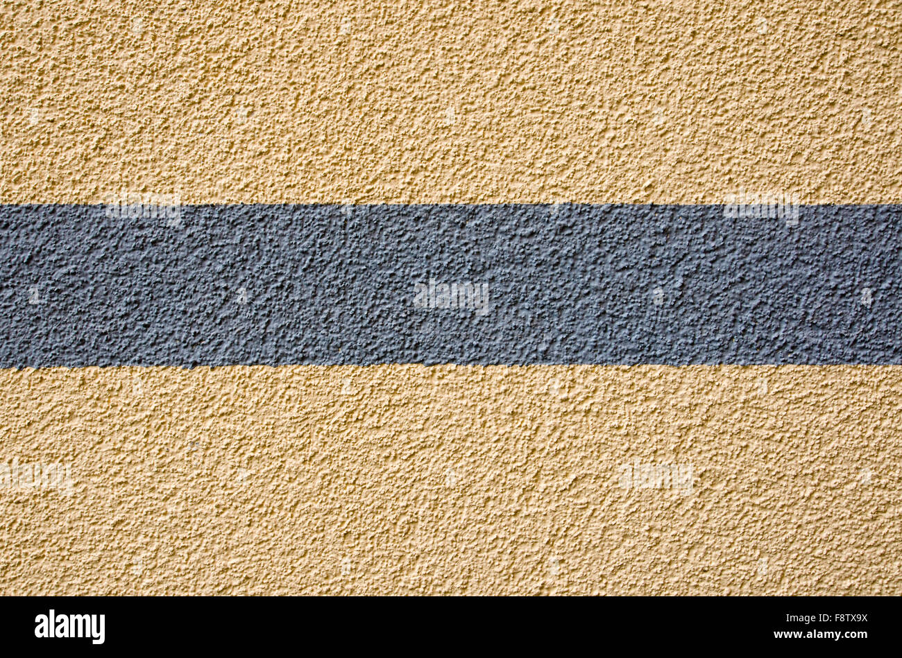 Un intonaco giallo a parete con una striscia grigia Foto Stock
