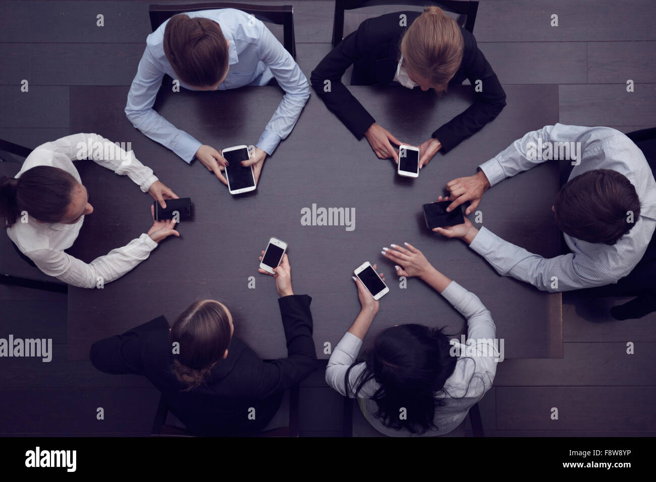 La gente di affari con gli smartphone seduti attorno al tavolo, vista dall'alto Foto Stock