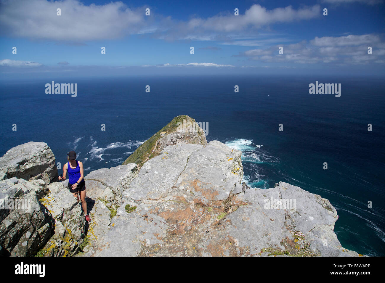 Una ragazza in piedi su una scogliera di Capo di Buona Speranza con l'Oceano Atlantico e il cielo in background Foto Stock