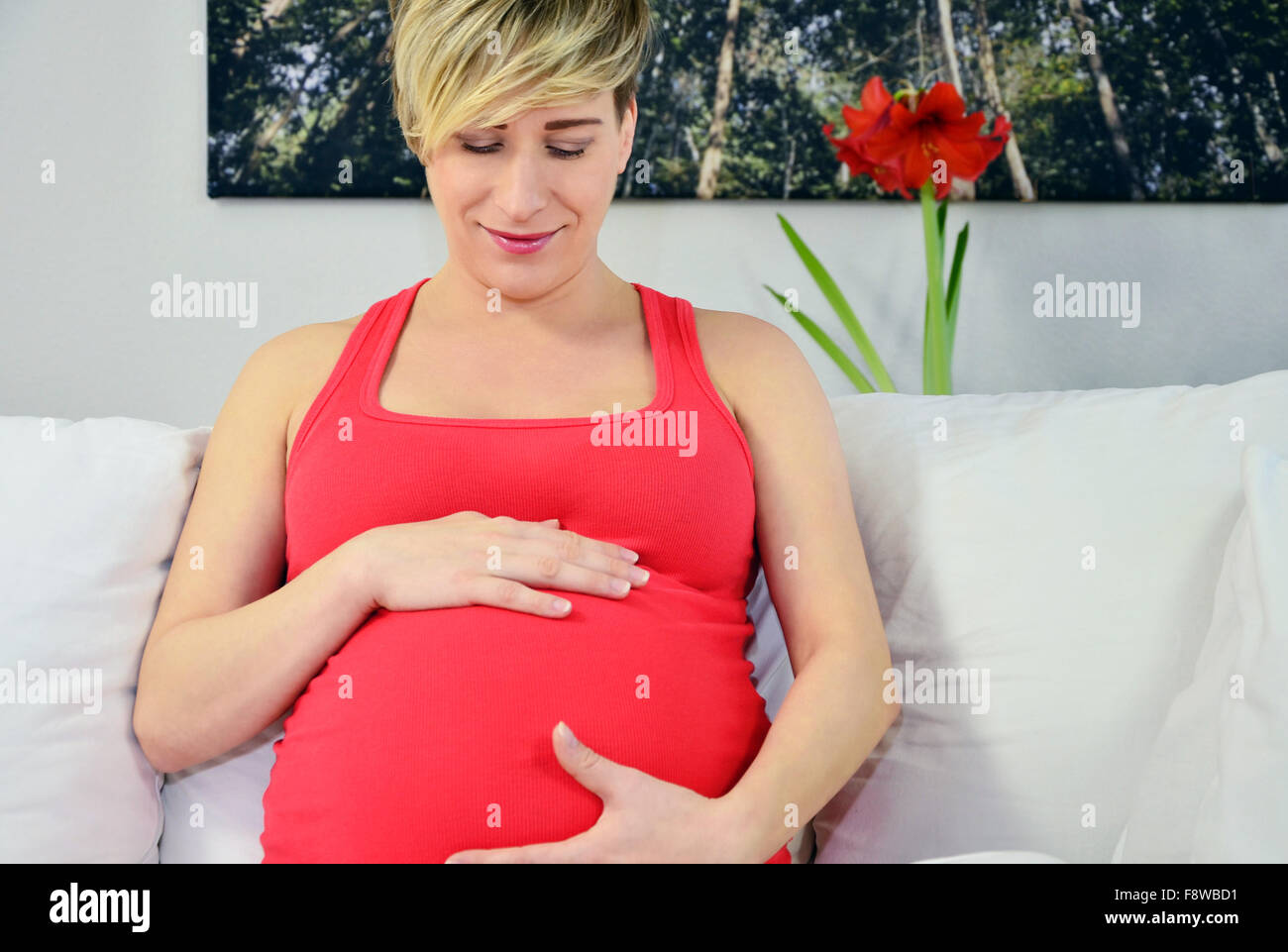 Donna incinta con twin bambinos, mani in ascolto dello stomaco Foto Stock