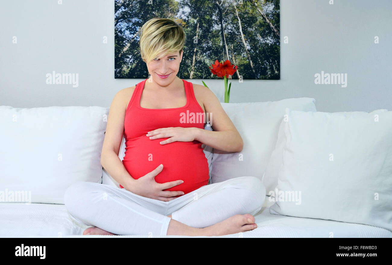 Donna incinta con twin bambinos, mani in ascolto dello stomaco Foto Stock