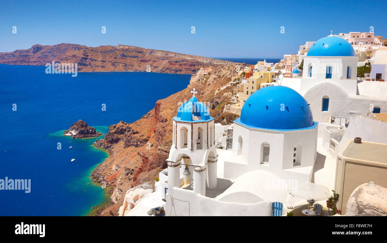 Bianco greco chiesa con cupola blu che si affaccia sul mare Egeo e la cittadina di Oia - Santorini, Cicladi, Grecia Foto Stock
