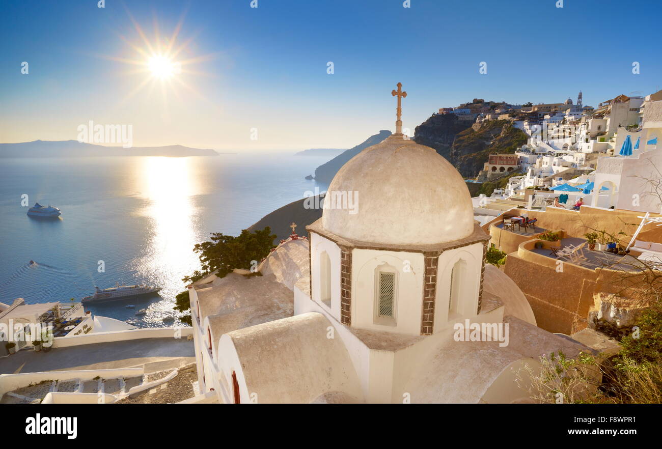 Thira (città capitale di Santorini) - greco chiesa bianca che si affaccia sul mare e il sole sul cielo blu - Santorini Island, Grecia Foto Stock