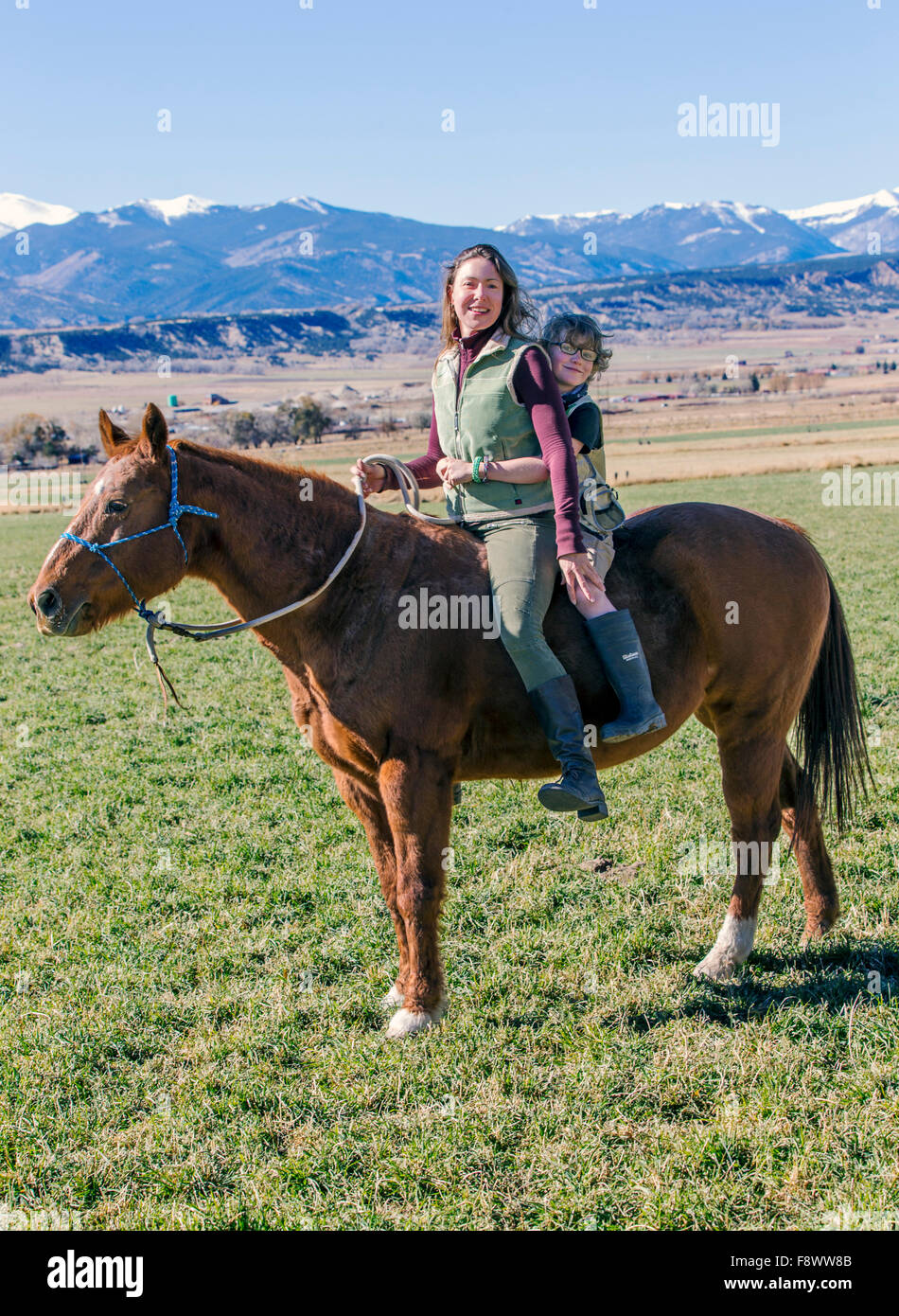 Attraente la madre e il giovane figlio di equitazione nel ranch dei pascoli Foto Stock