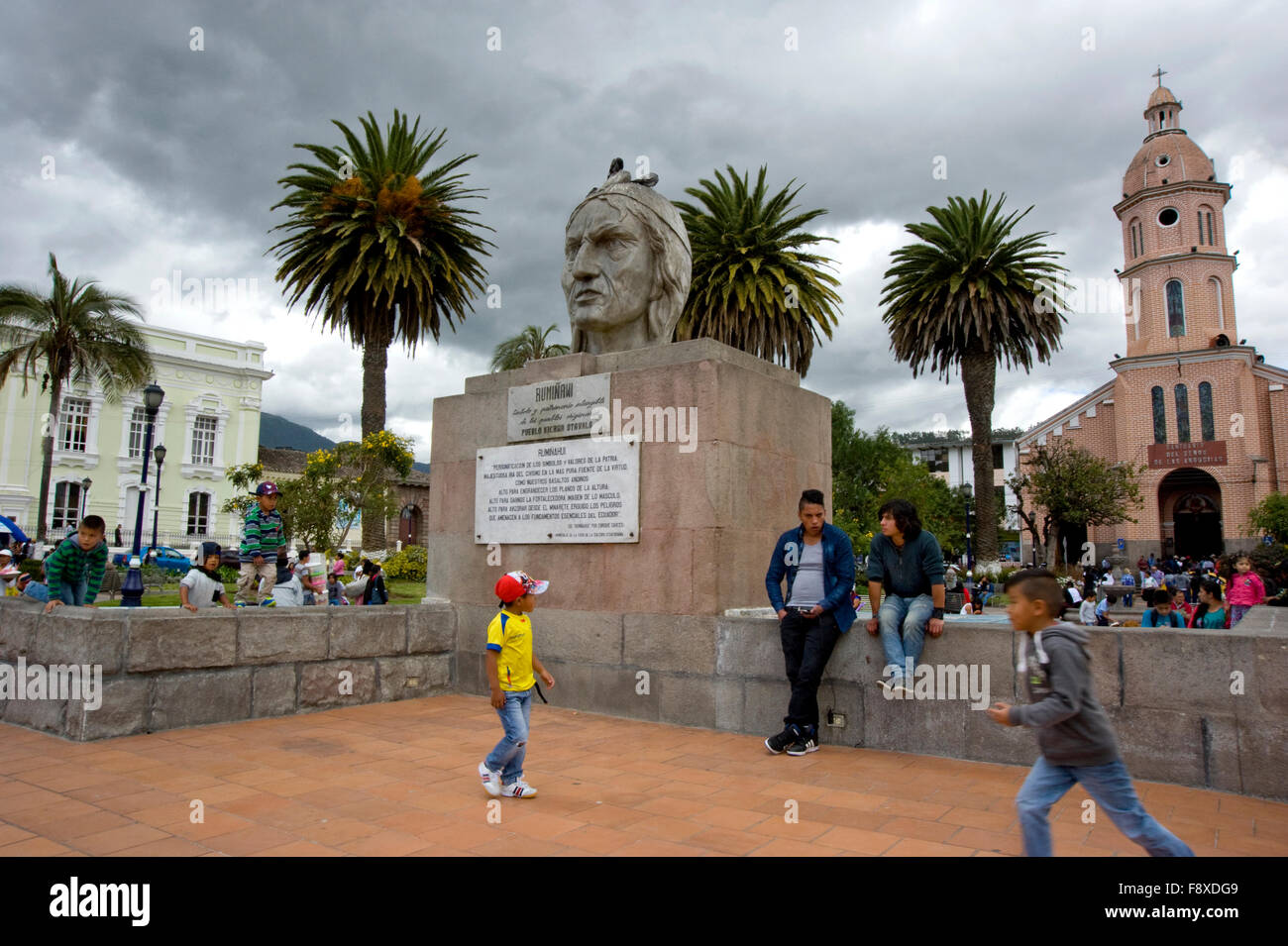 Bambini che giocano vicino alla statua nella piazza pubblica di Otavalo, Ecuador Foto Stock