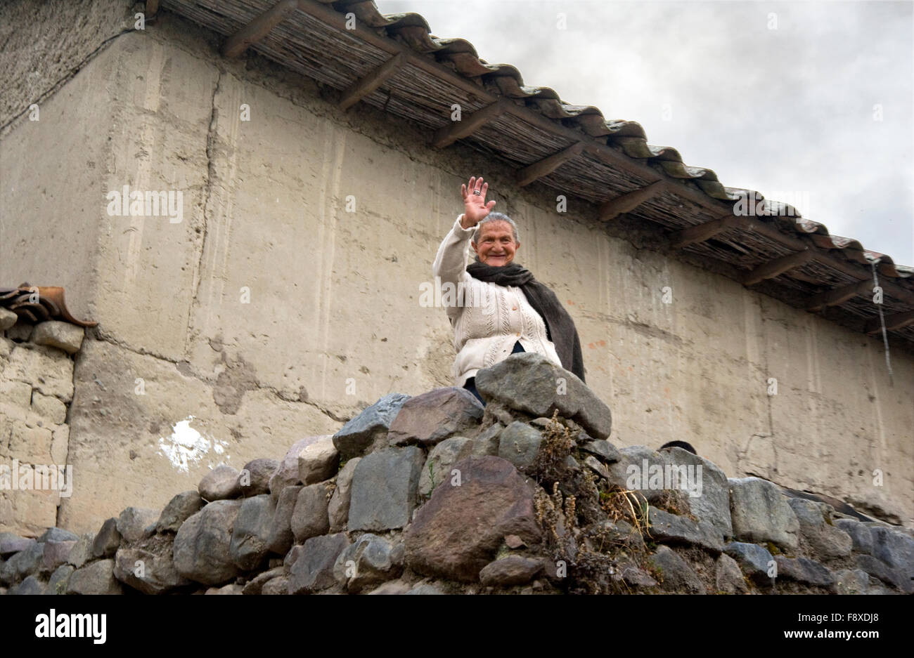 Una donna anziana su un balcone in pietra orologi un treno passare in rotta verso Salinas da Ibarra, Ecuador Foto Stock