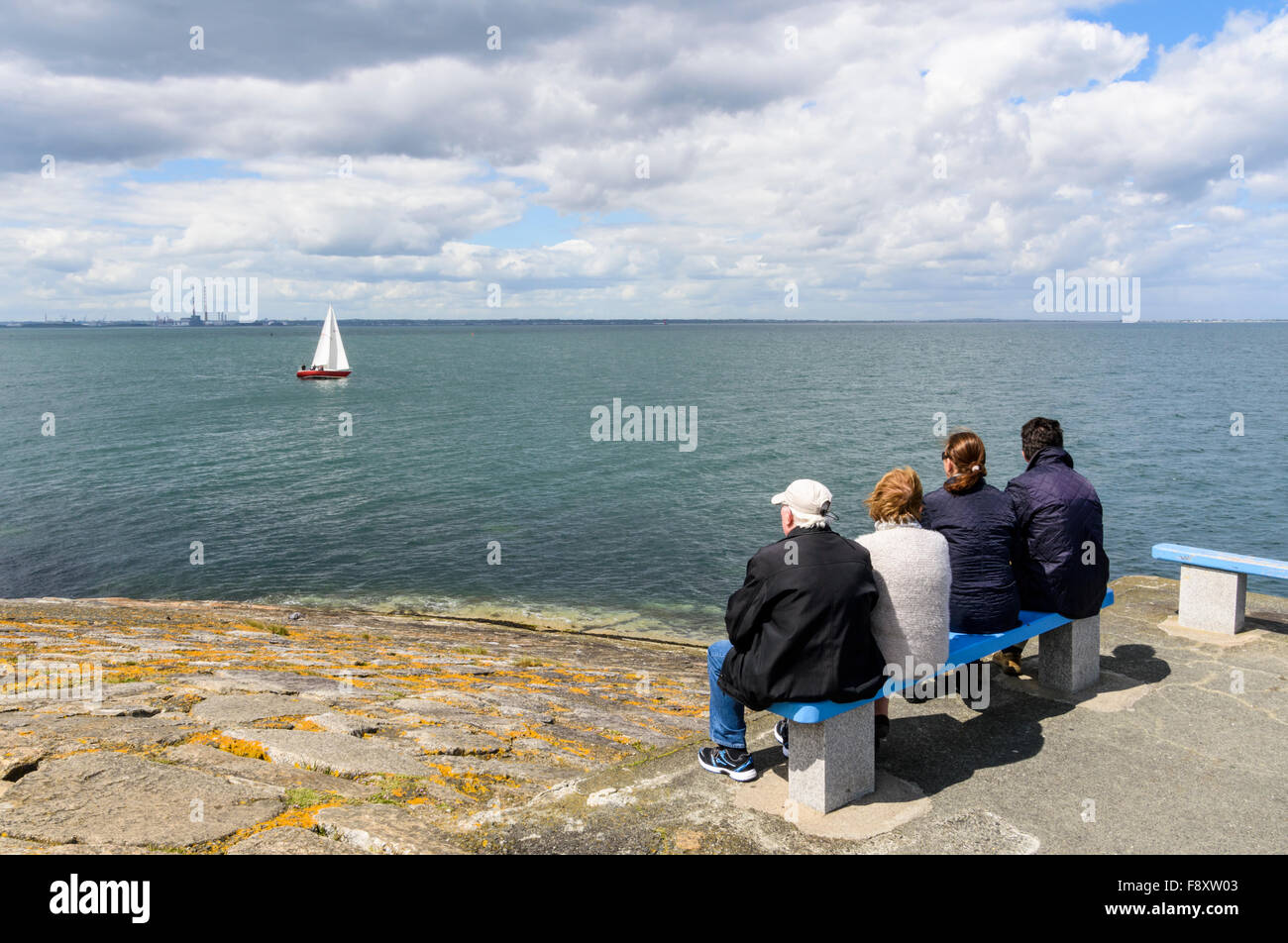 Persone seduto su una panchina alla fine di Dun Laoghaire ad est del molo, Dun Laoghaire, Dun Laoghaire-Rathdown, Leinster, Irlanda Foto Stock