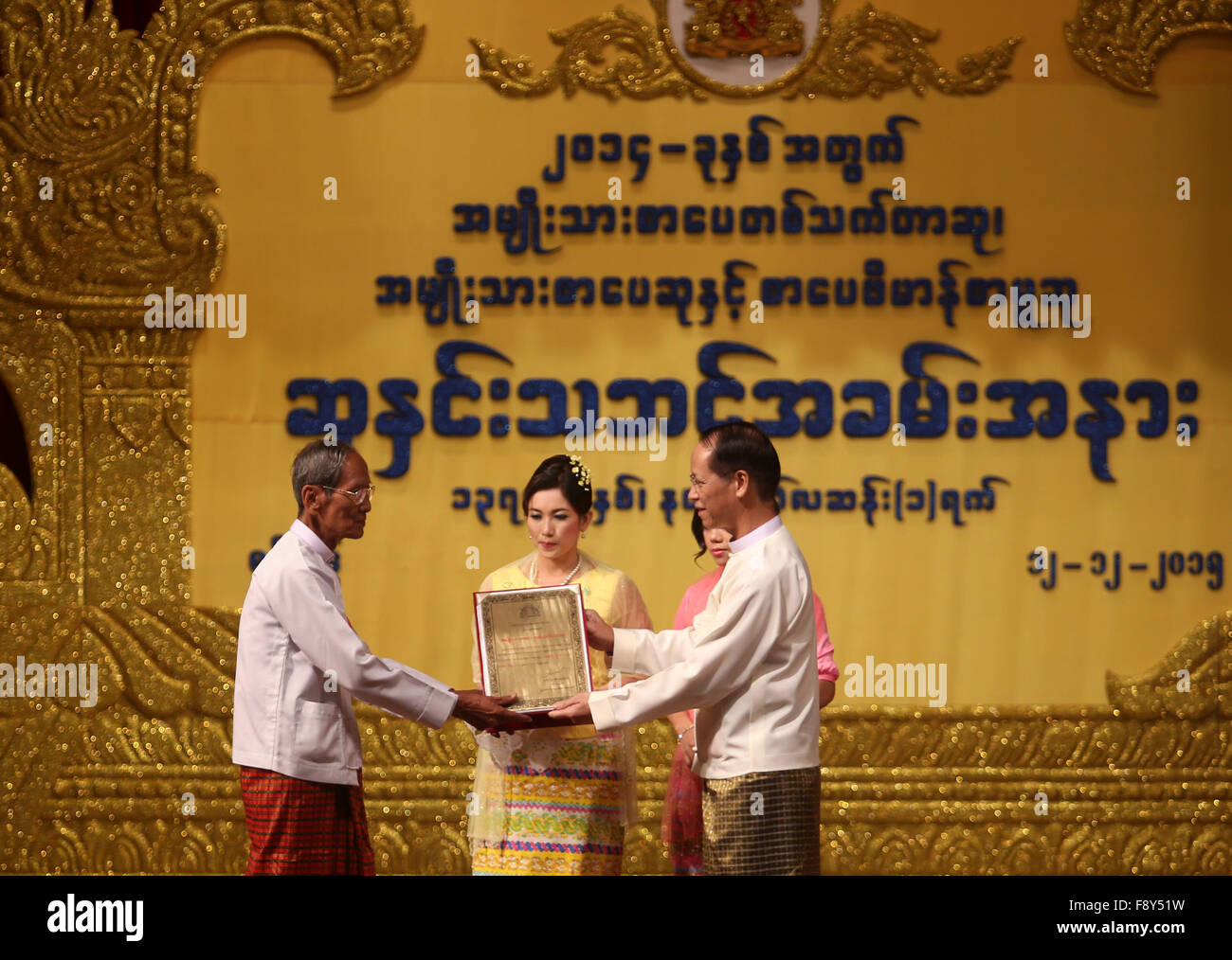 (151212) -- YANGON, Dic 12, 2015 (Xinhua) -- Myanmar Vice Presidente Dott. Sai Mauk Kham (R) anteriore presenta il Premio letterario nazionale per un vincitore letteraria presso il Teatro Nazionale di Yangon, Myanmar, Dic 12, 2015. Complessivamente 18 letterati nazionale ha vinto premi letterari (NLA) per 2014 in Myanmar, il Premio Letterario Nazionale comitato di controllo ha annunciato il Sabato. (Xinhua/U Aung) Foto Stock