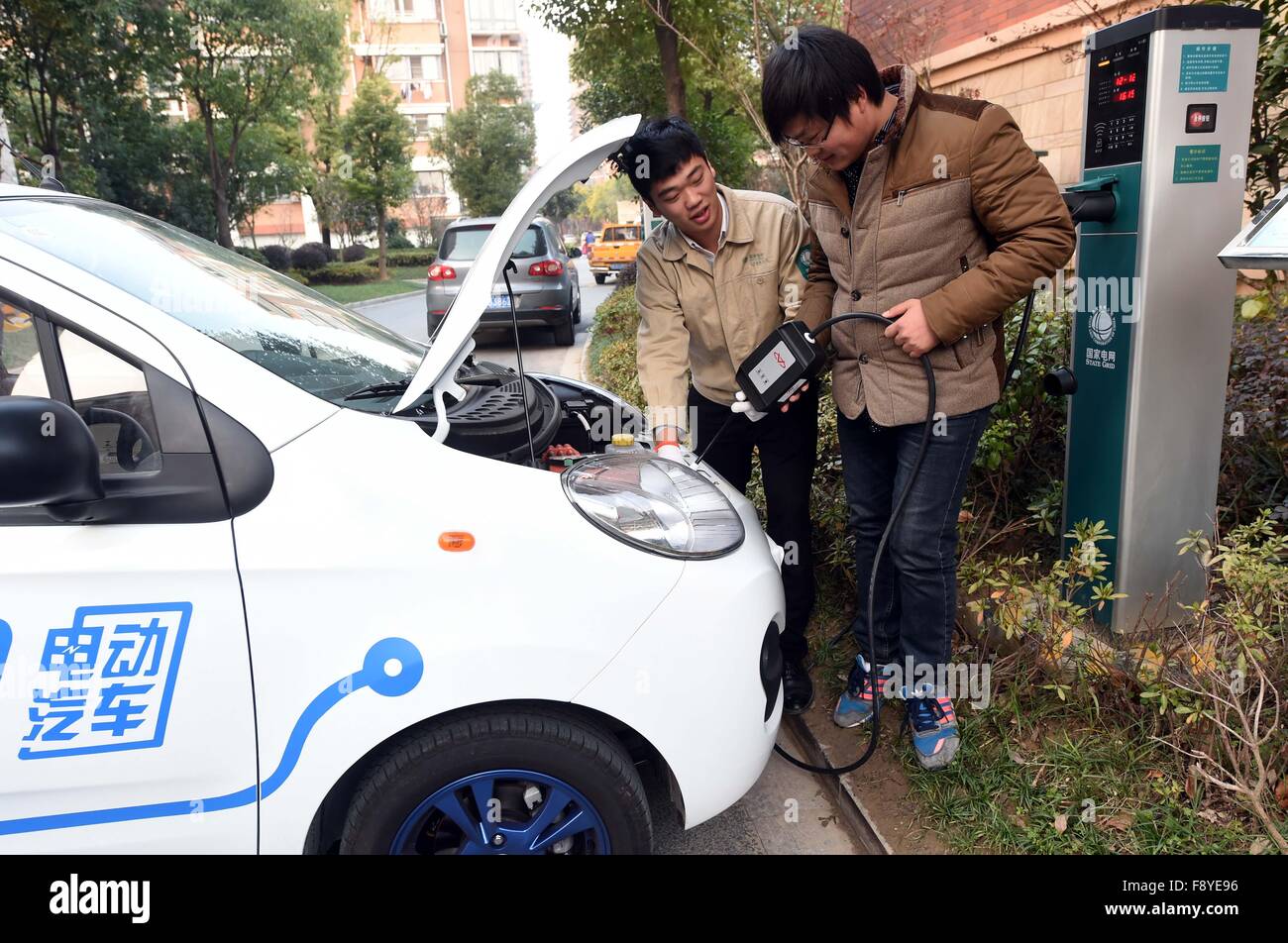 (151212) --(TAIZHOU JIANGSU), Dicembre 12, 2015 (Xinhua) -- Un autista(anteriore) impara a utilizzare il veicolo elettrico la carica pila presso la Comunità Hanlinyaju in Taizhou, est della Cina di provincia dello Jiangsu, a Dic. 12, 2015. La comunità ha sviluppato il veicolo elettrico sistema di carica mediante il quale i conducenti possono utilizzare le app in primo piano. software per caricare il veicolo e di pagare la tassa. Un totale di 130 veicoli elettrici pali di carica sono state già impostato in Taizhou City. (Xinhua/Li Xiaoguo)(up) Foto Stock