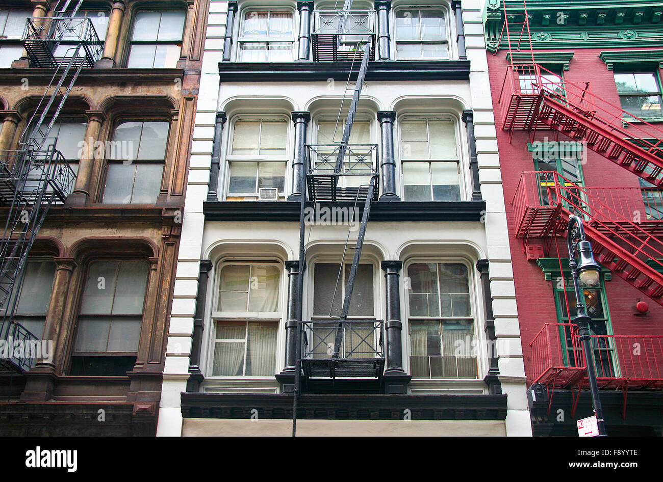 Tre colorate, rosso, marrone e bianco, appartamento facciate di edifici con fughe di emergenza. Tipico di New York City di complessi di noleggio Foto Stock