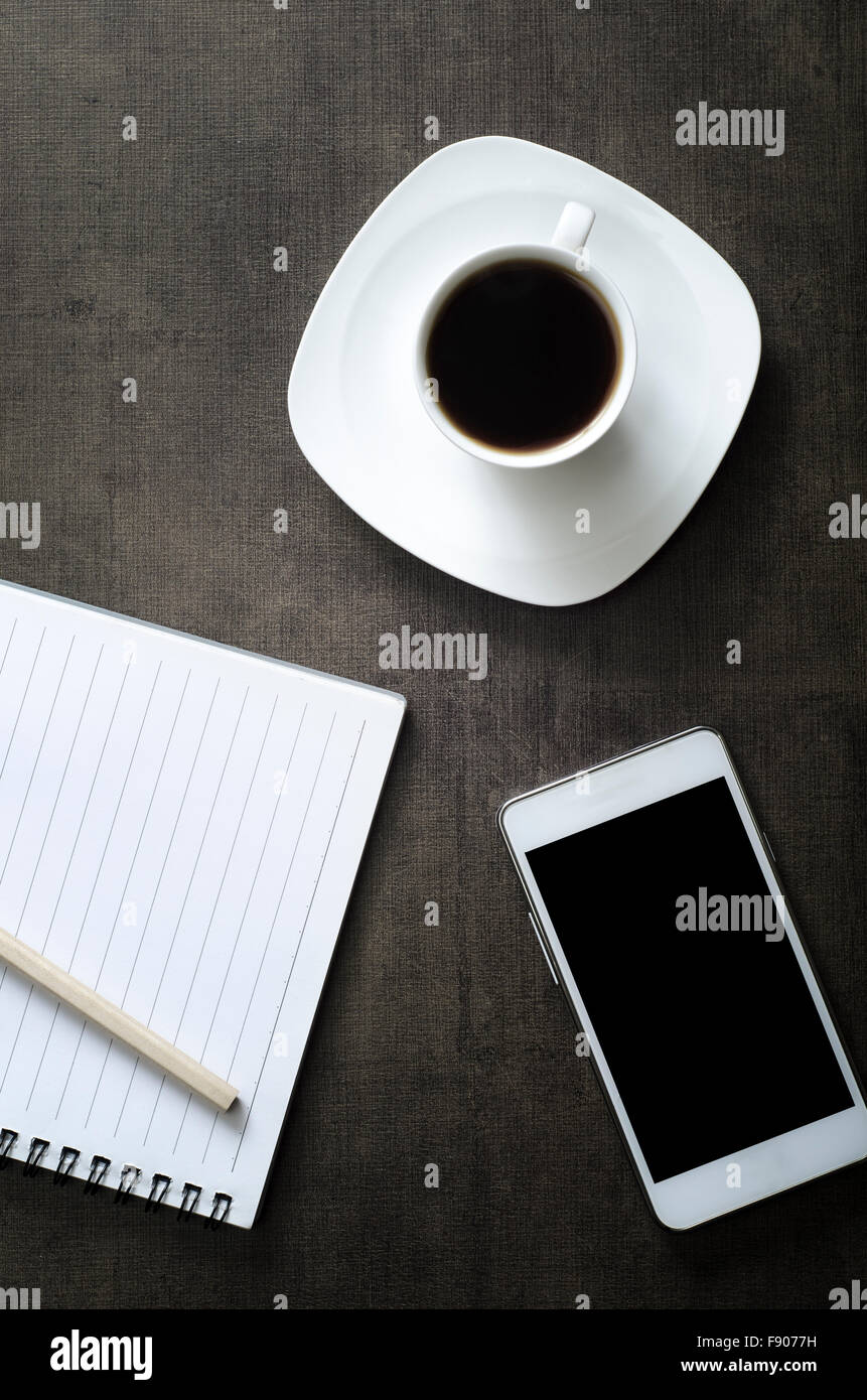 Smartphone con notebook e la tazza di caffè su sfondo di legno. , Dal di sopra Foto Stock
