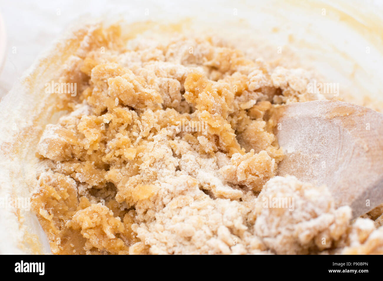 Close-up di pasta biscotto è mescolato con un cucchiaio di legno Foto Stock