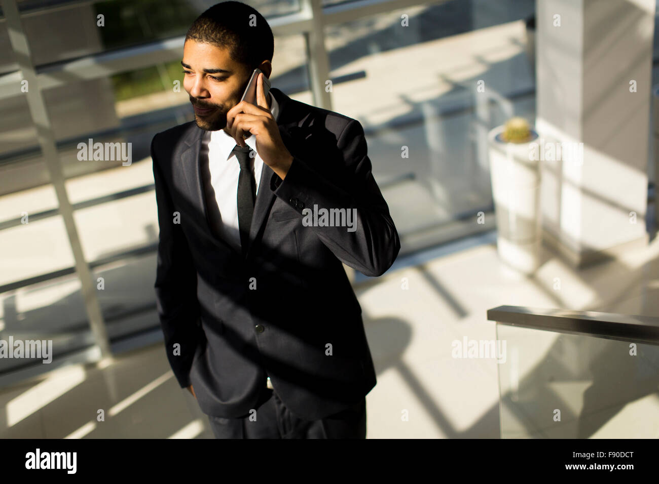 Bel giovane uomo nero con il cellulare in ufficio Foto Stock