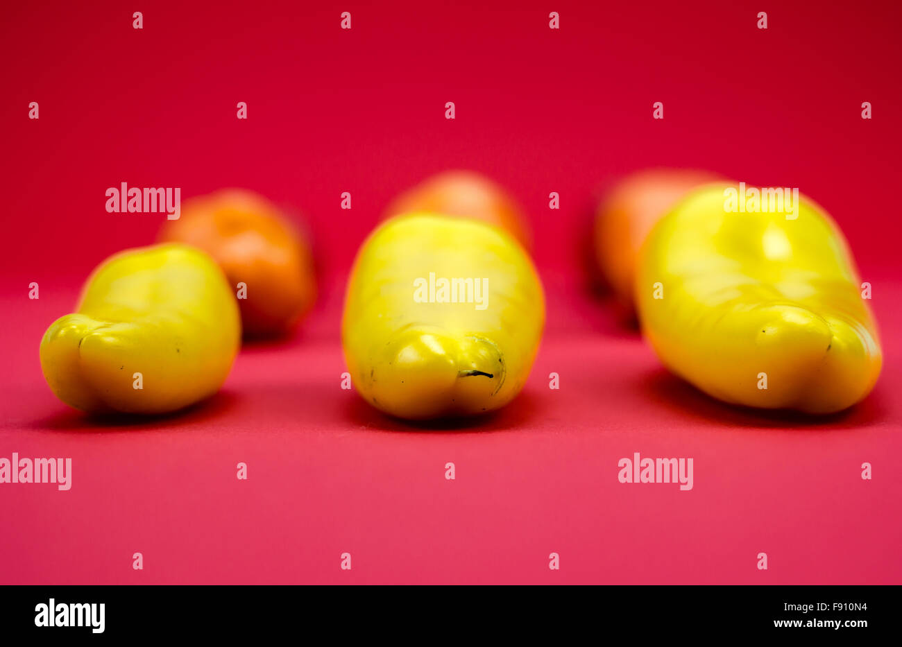 Gruppo di giallo, arancione e peperoni rossi su sfondo rosso Foto Stock