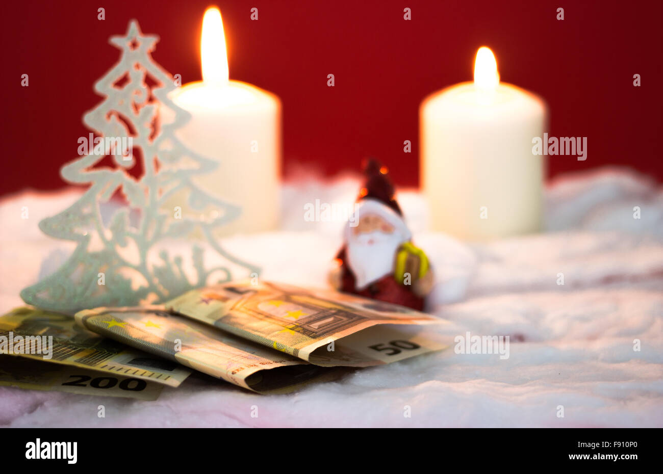 Babbo Natale con candele accese e denaro su sfondo rosso Foto Stock