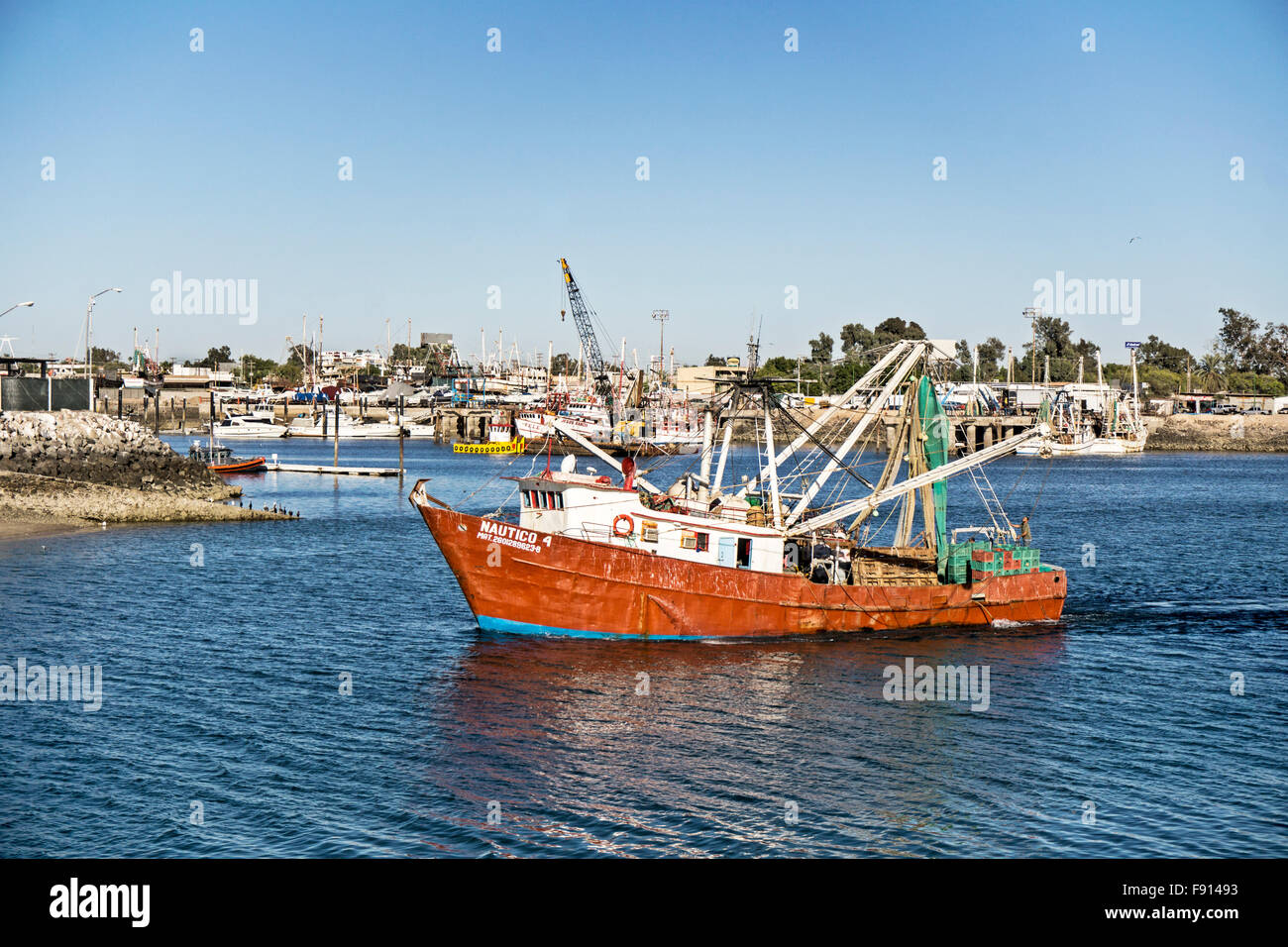 Jaunty vecchia barca da gamberetti shrimper con arancia lamiera verniciata metal clad hull & bracci ripiegati capi fuori da Puerto Penasco porto vecchio Foto Stock