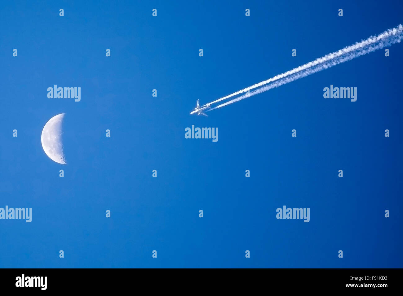 Volo aereo passato la luna contro il luminoso cielo blu Foto Stock