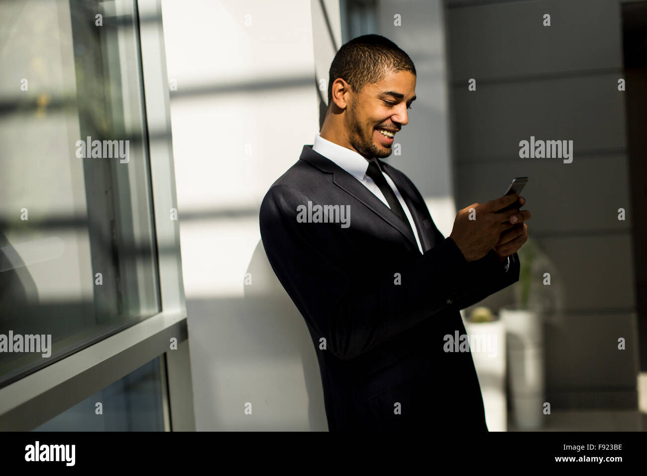 Bel giovane uomo nero con il cellulare in ufficio Foto Stock