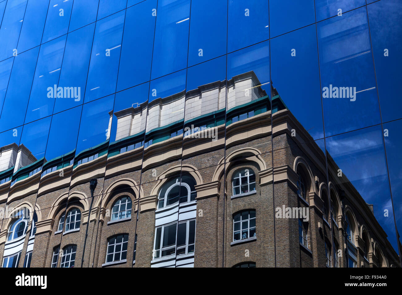 Riflessioni del vecchio edificio e cielo blu riflessa nella facciata di vetro di un moderno blocco uffici a Londra, Inghilterra, Regno Unito Foto Stock