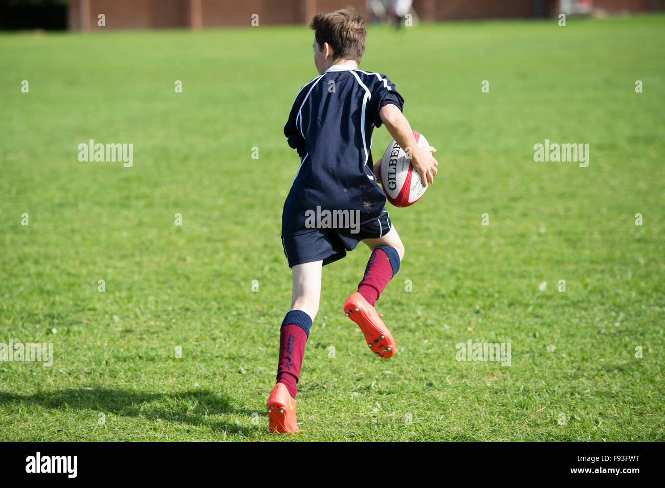 Istruzione secondaria Wales UK: educazione fisica lezione - un ragazzo adolescente giocando a rugby su una scuola giochi campo di passo. Foto Stock