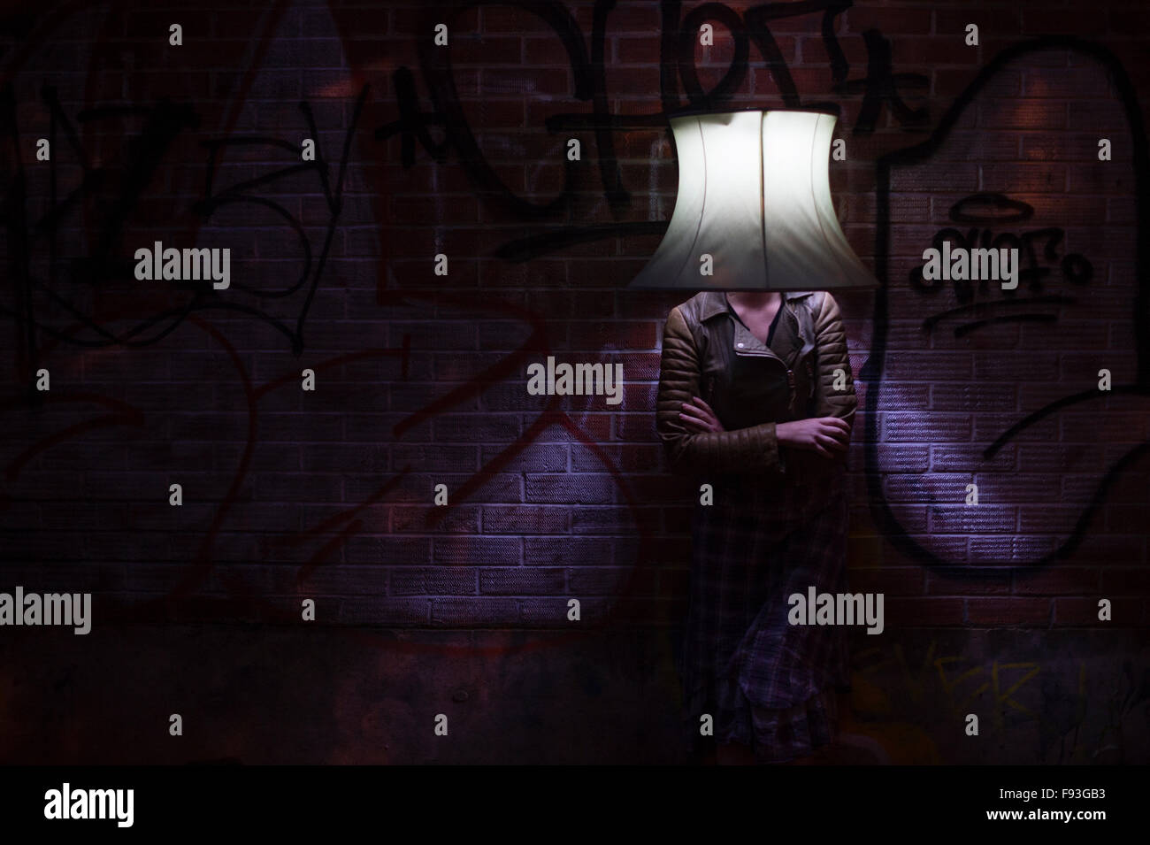 Una donna sola ragazza indossare copricapi dispari: un paralume illuminato sul suo capo all'aperto al crepuscolo Foto Stock