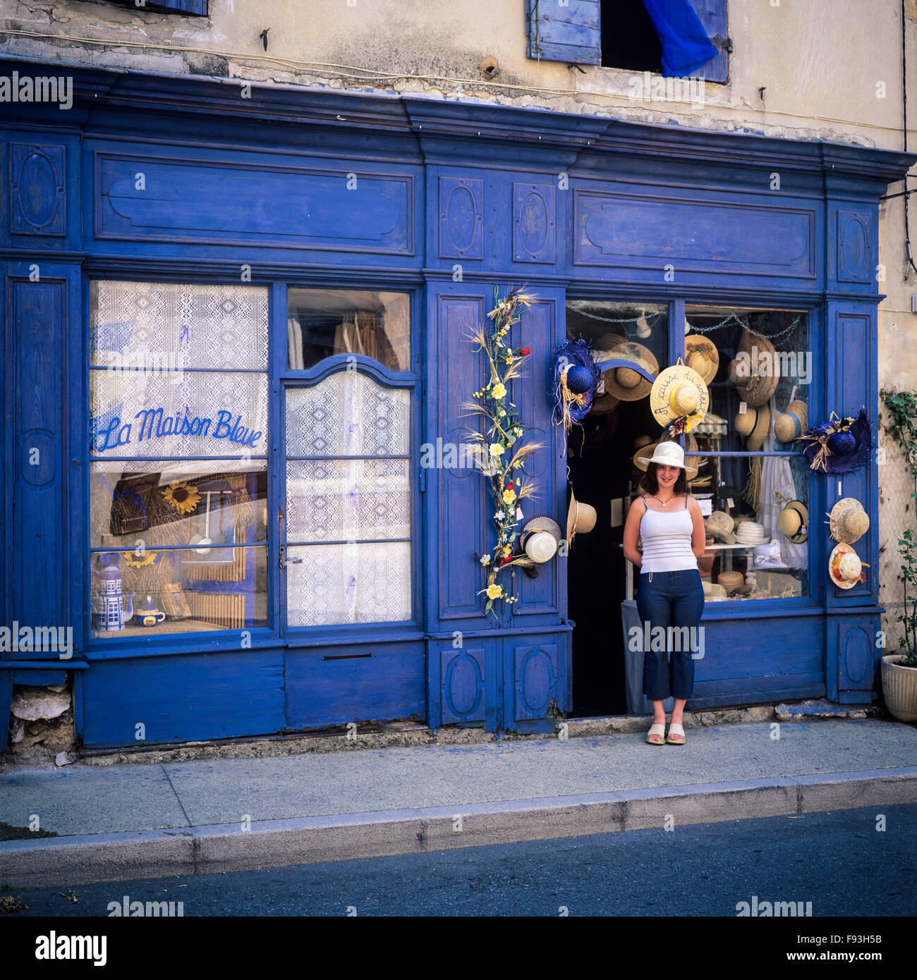 Ragazza pone di fronte " La Maison Bleue", la Casa Blu, il sole e il cappello di paglia shop, Sault, Vaucluse Provence, Francia Foto Stock