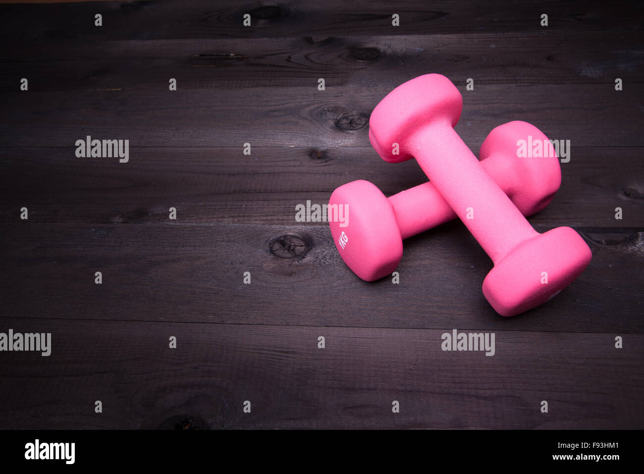 Attrezzature sportive. Rosa di pesi su un nero lo sfondo di legno Foto Stock