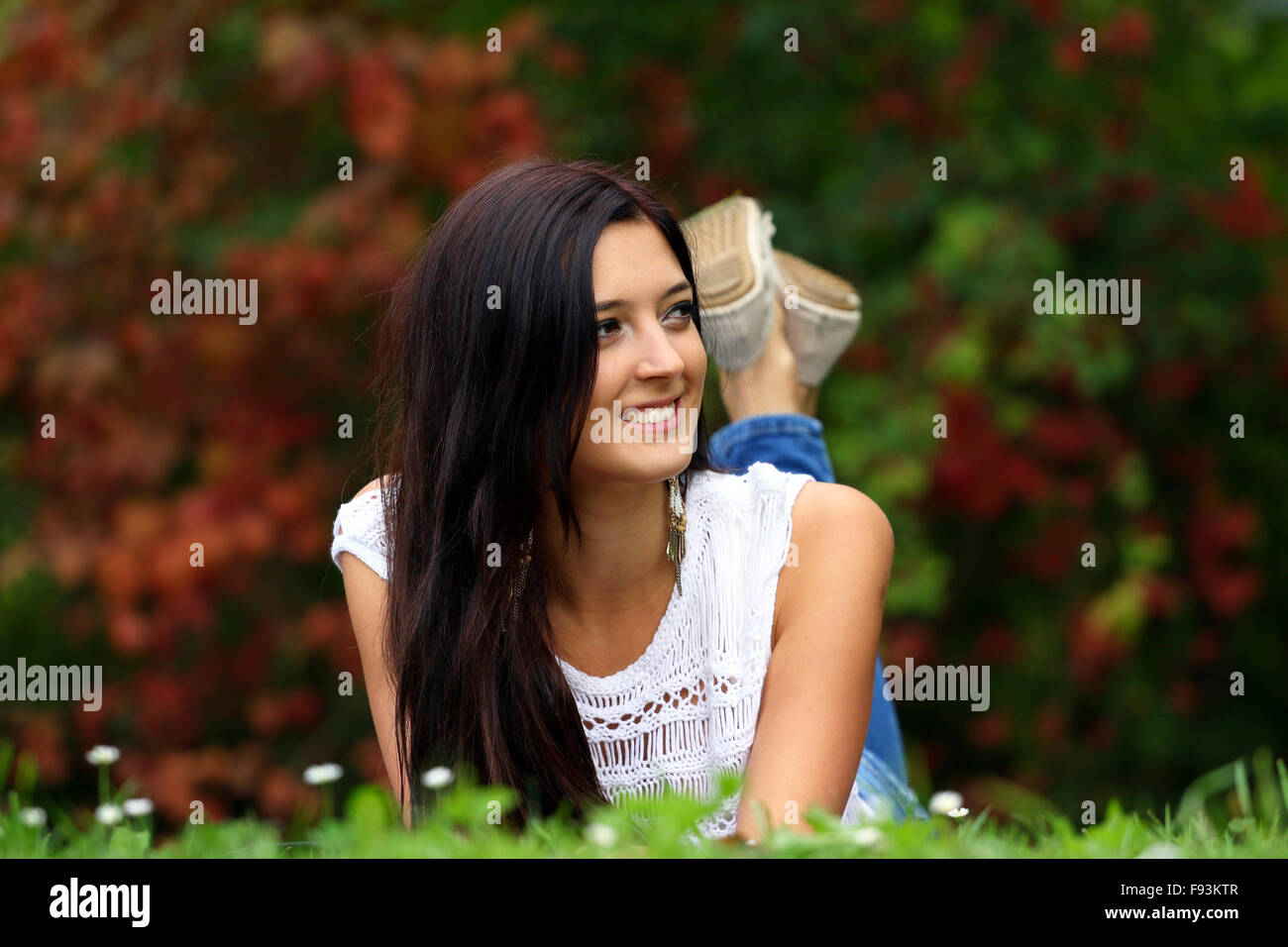 Bella bruna fantasticando nel parco sdraiarsi sull'erba. Foto Stock