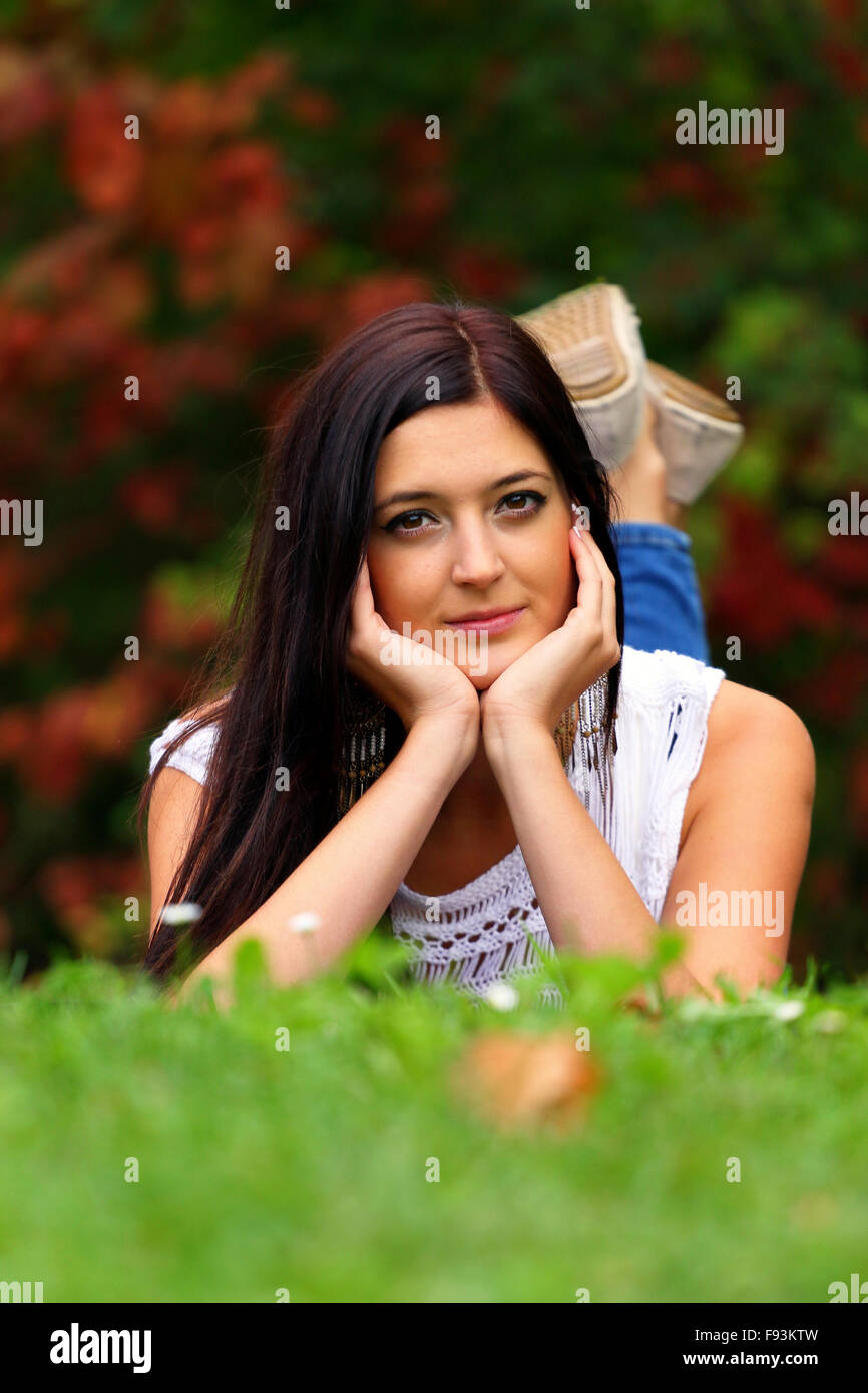 Bella bruna fantasticando nel parco sdraiarsi sull'erba. Foto Stock