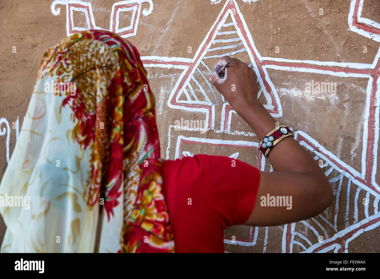 Donna facendo pittura decorativa sulla parete per il cammello di Pushkar Fair, Rajesthan, India Foto Stock