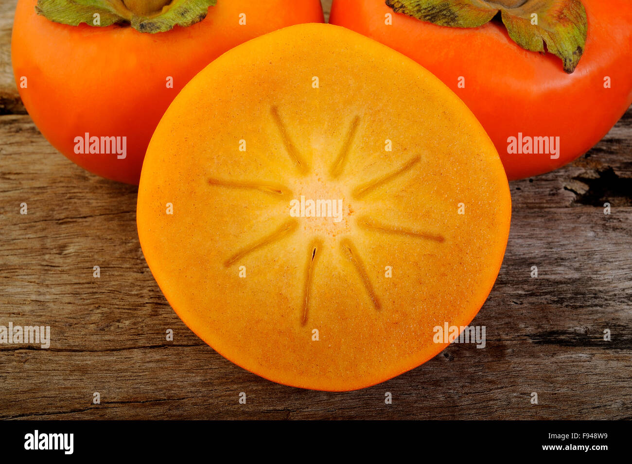 Affettare frutta persimmon su sfondo di legno Foto Stock