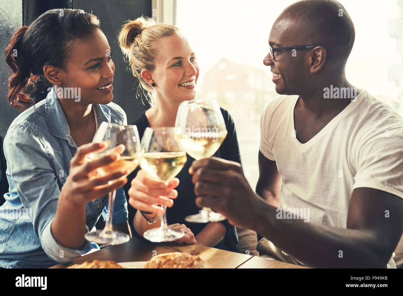 Etnia amici in un bar a bere vino e mangiare tapas Foto Stock