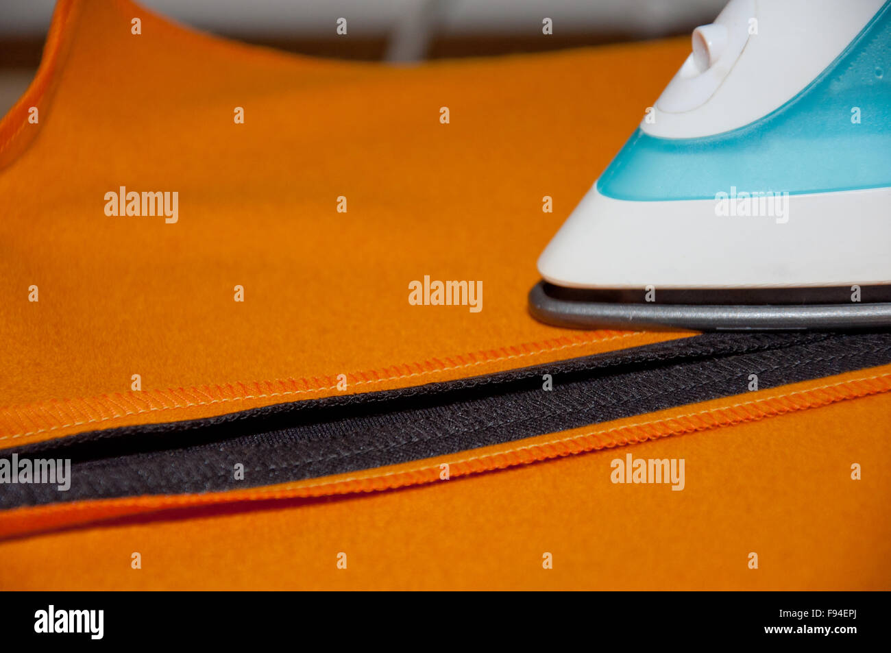 Lavori domestici stiratura arancione e il panno nero in ambienti interni Foto Stock