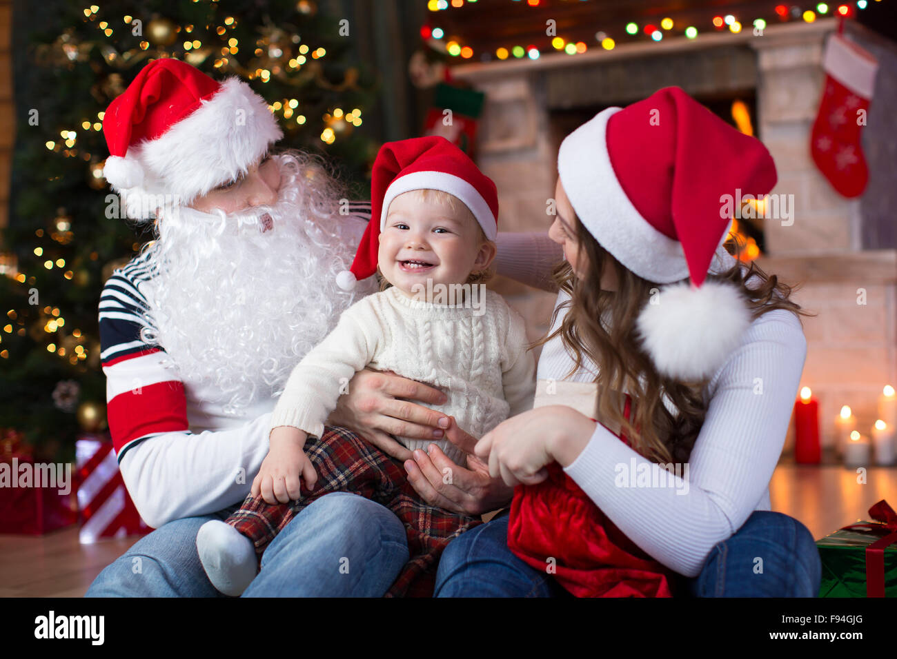 La famiglia felice con bambino figlio avente un divertimento vicino a albero di Natale e caminetto in soggiorno Foto Stock