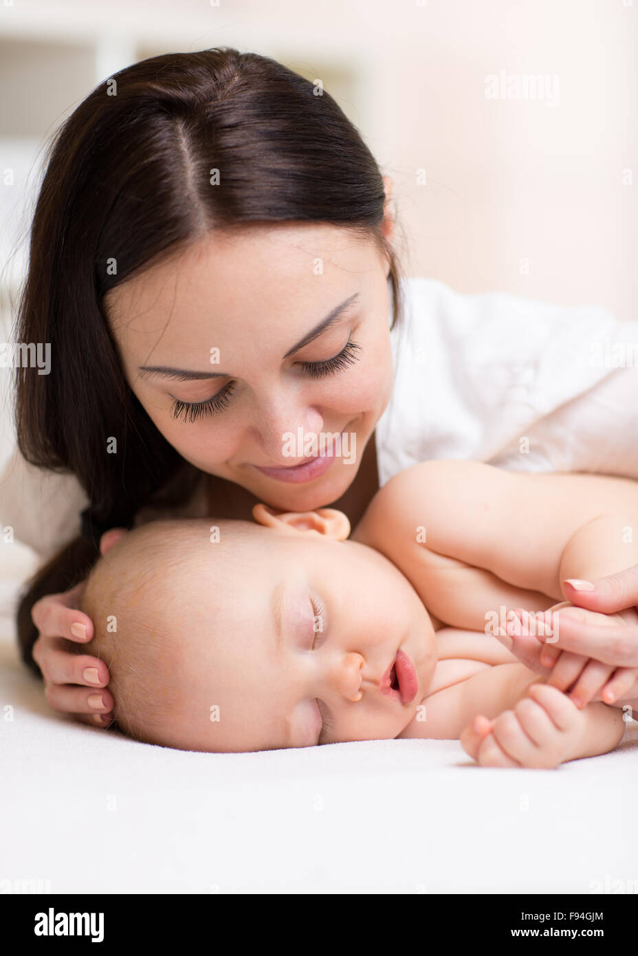 Felice bella donna guardando il suo figlio che dorme baby Foto Stock