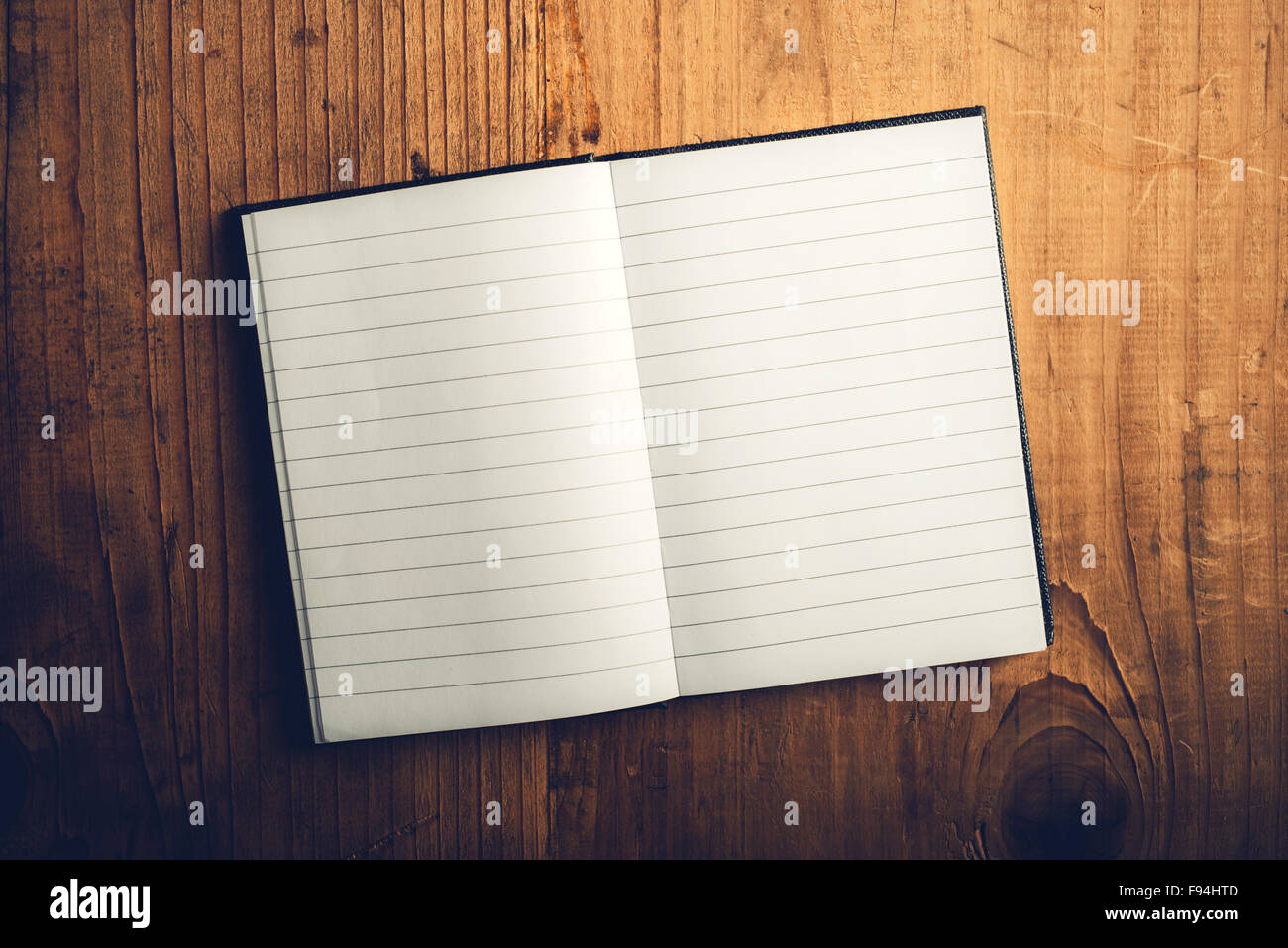 Vista superiore del notebook aperto con pagine vuote sulla vecchia scrivania in legno, dai toni rétro immagine come spazio di copia Foto Stock