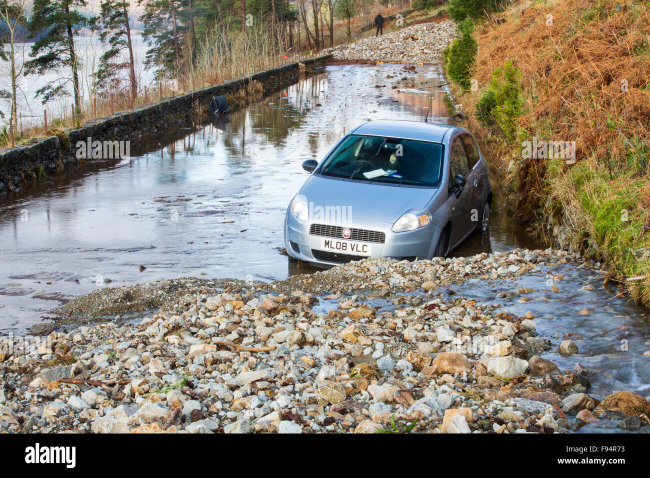 Un automobile intrappolata tra due frane sulla A591, la strada principale che attraversa il distretto del lago, che era stato completamente distrutto dalle inondazioni da Storm Desmond, Cumbria, Regno Unito. La strada è stata superata in molti luoghi da frane e pareti di flood debirs venti metri di alta. La strada sarà probabilmente chiusa per mesi. Tenuto domenica 6 dicembre 2015. Foto Stock