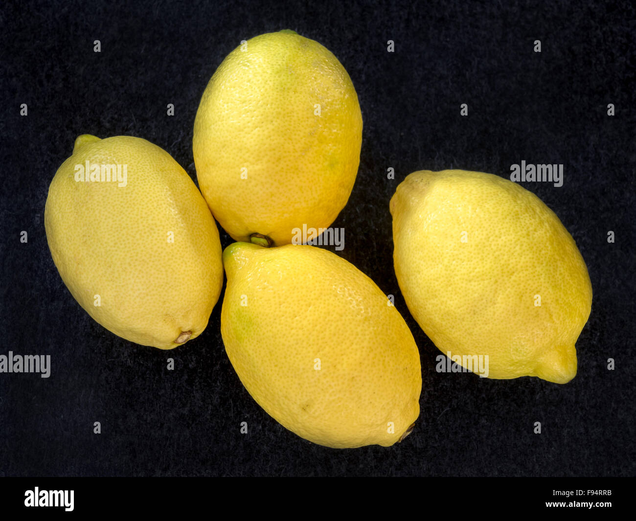 Quattro limoni maturi su uno sfondo grigio scuro Foto Stock