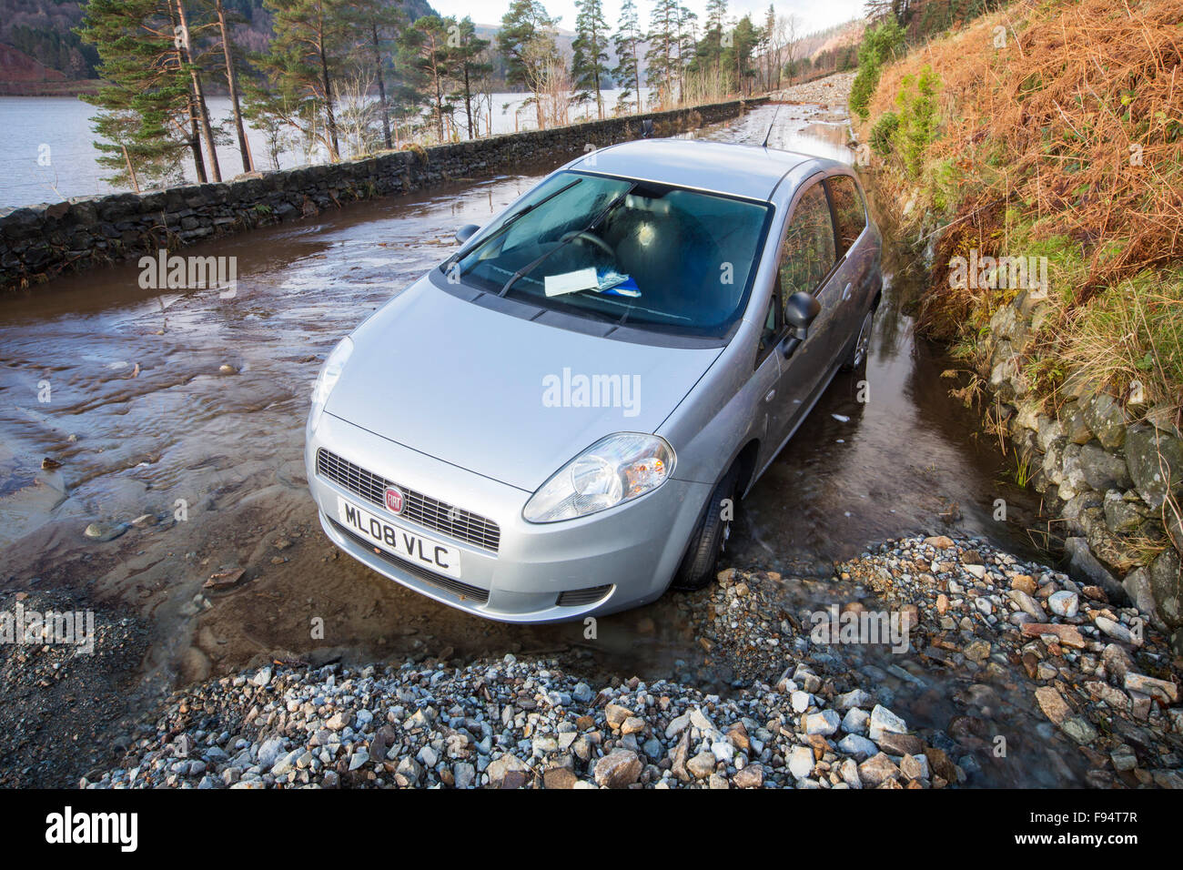 Un automobile intrappolata tra due frane sulla A591, la strada principale che attraversa il distretto del lago, che era stato completamente distrutto dalle inondazioni da Storm Desmond, Cumbria, Regno Unito. La strada è stata superata in molti luoghi da frane e pareti di flood debirs venti metri di alta. La strada sarà probabilmente chiusa per mesi. Tenuto domenica 6 dicembre 2015. Foto Stock