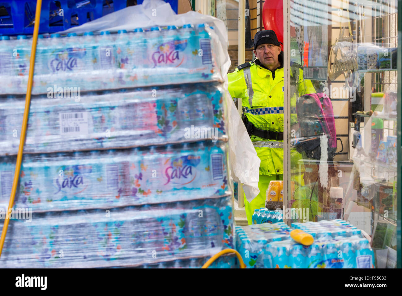 Sabato 5 dicembre 2015, Storm desmond si è schiantato nel Regno Unito, la produzione del Regno Unito più alto mai 24 ore totali di precipitazione a 341.4mm. Ha allagato il Lakeland Village Glenridding, che si stava appena cominciando a riparazione quando un altro periodo di heavy rain per mercoledì 9 dicembre hanno causato la Glenridding Beck di scoppiare le sue banche, provocando ulteriore distruzione. Questa foto scattata la mattina di giovedì 1Oth Dicembre mostra un poliziotto si fermò accanto a materiali di consumo di acqua in bottiglia. È ironico che dopo tanta pioggia, il paese non dispone di acqua potabile, la fornitura è stata tagliata dalle inondazioni. Foto Stock