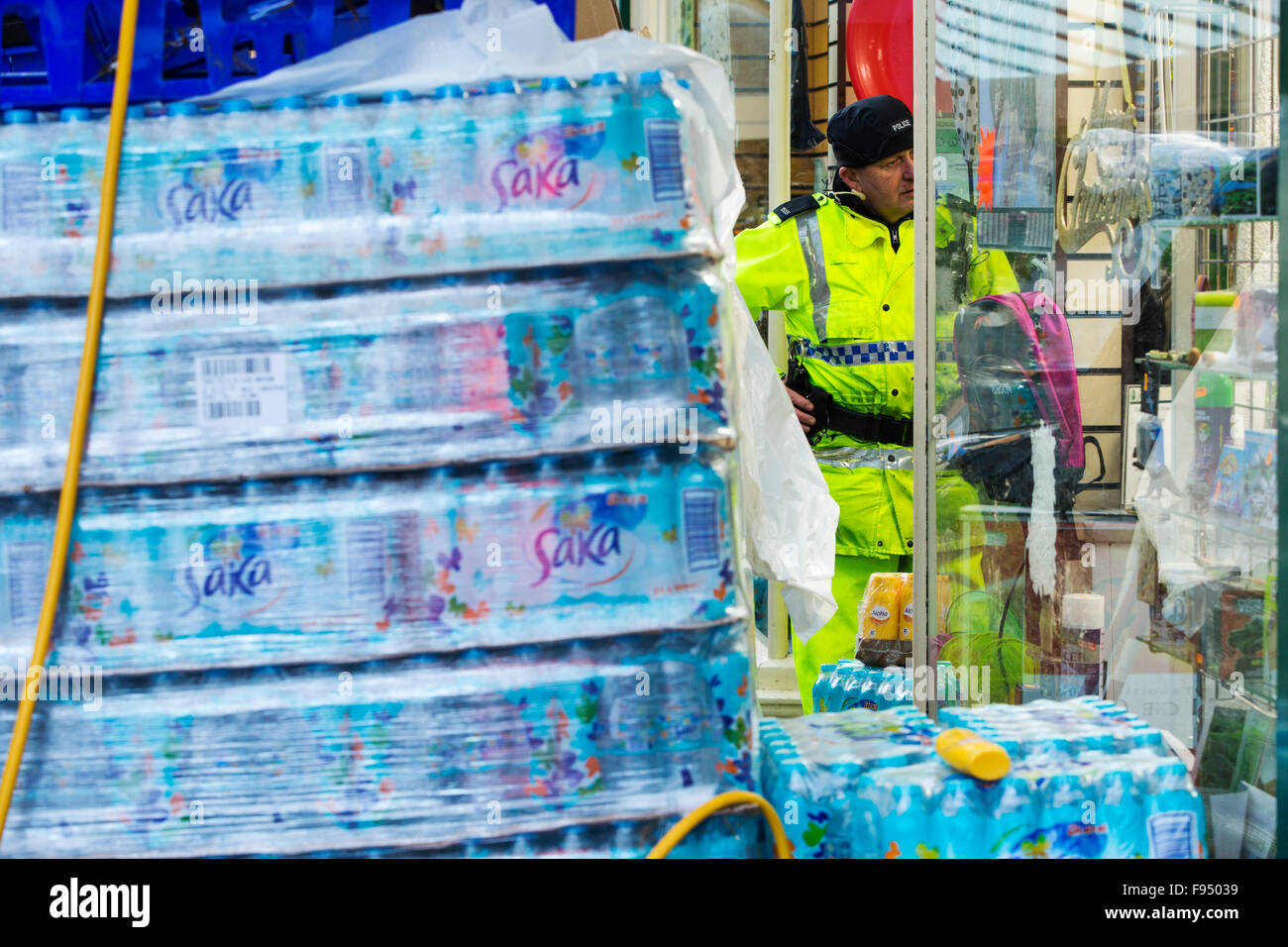 Sabato 5 dicembre 2015, Storm desmond si è schiantato nel Regno Unito, la produzione del Regno Unito più alto mai 24 ore totali di precipitazione a 341.4mm. Ha allagato il Lakeland Village Glenridding, che si stava appena cominciando a riparazione quando un altro periodo di heavy rain per mercoledì 9 dicembre hanno causato la Glenridding Beck di scoppiare le sue banche, provocando ulteriore distruzione. Questa foto scattata la mattina di giovedì 1Oth Dicembre mostra un poliziotto si fermò accanto a materiali di consumo di acqua in bottiglia. È ironico che dopo tanta pioggia, il paese non dispone di acqua potabile, la fornitura è stata tagliata dalle inondazioni. Foto Stock